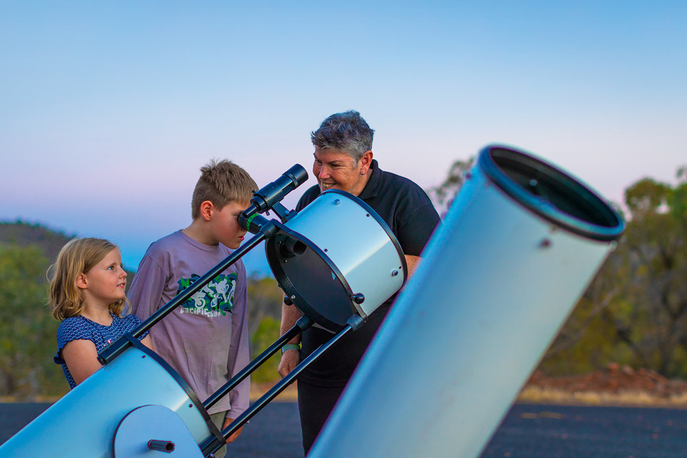 Astronomer Donna Burton teaches country kids Clayton and Joni about the stars, with the help of a 12-inch Dobsonian telescope. Photo Josh Smith. Great Australians 2019.
