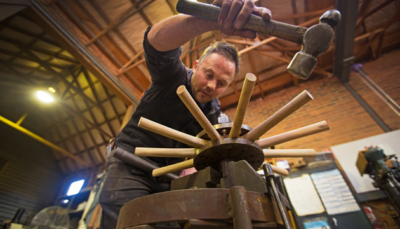 Mick Dando works on a reproduction vintage car wheel.
